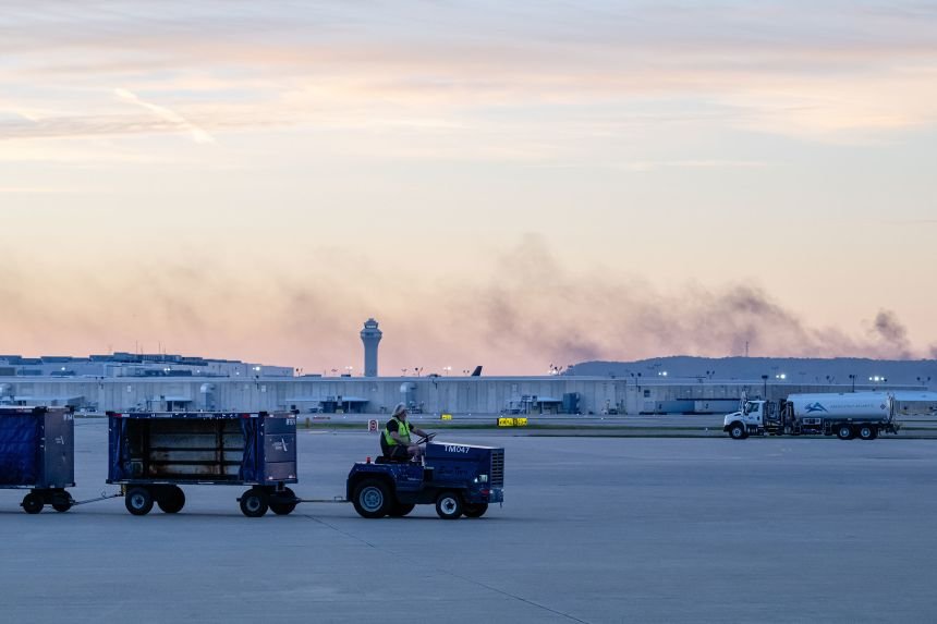 The ATC tower is seen while smoke rises from the crash site of UPS Flight 2796 near Louisville Muhammad Ali International Airport on Wednesday. Jon Cherry/AP